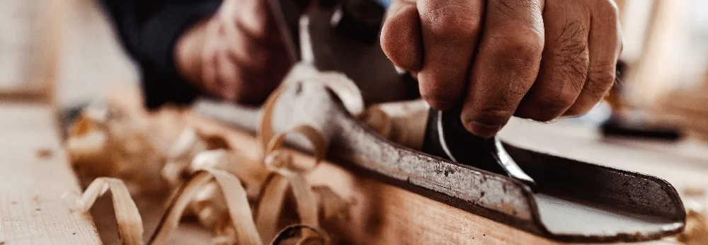 Person hobelt Holz mit einem Hobel